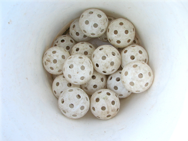 Figure 5: Example of porous rock: A bucket of plastic baseballs with holes, also known as wiffle balls. This bucket will hold more water than if it were filled with solid baseballs [5].