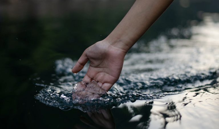 Photograph of a hand passing through a pool of water