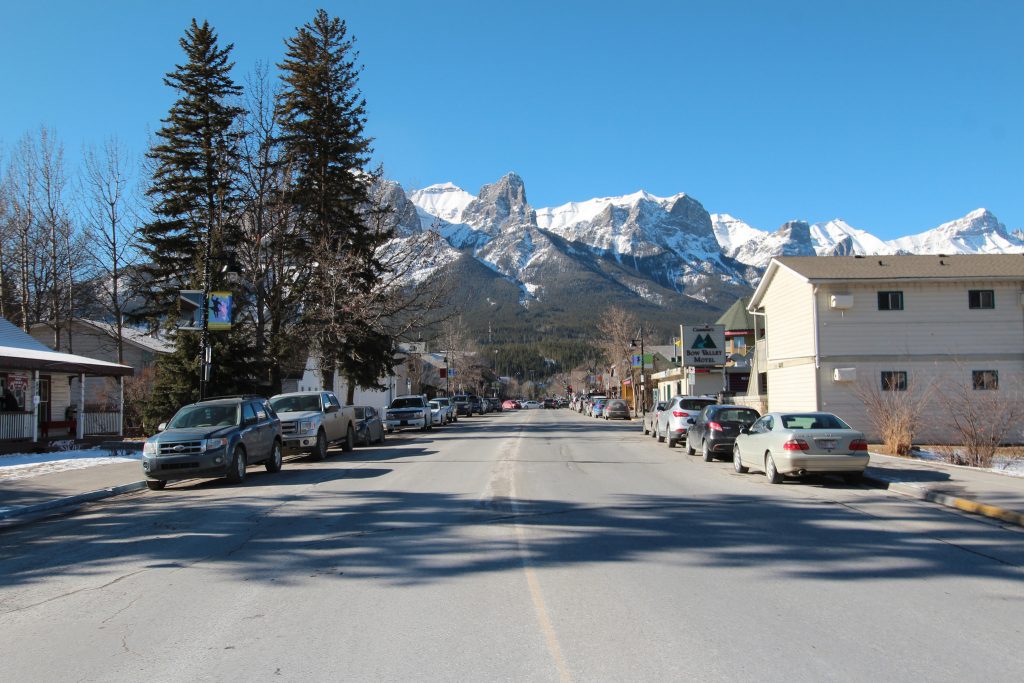 Photograph looking the length of a quiet street at some mountains of Canmore.