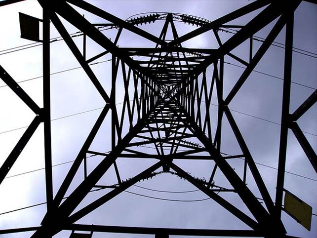 A photo looking upwards from within the base of a large power pylon.