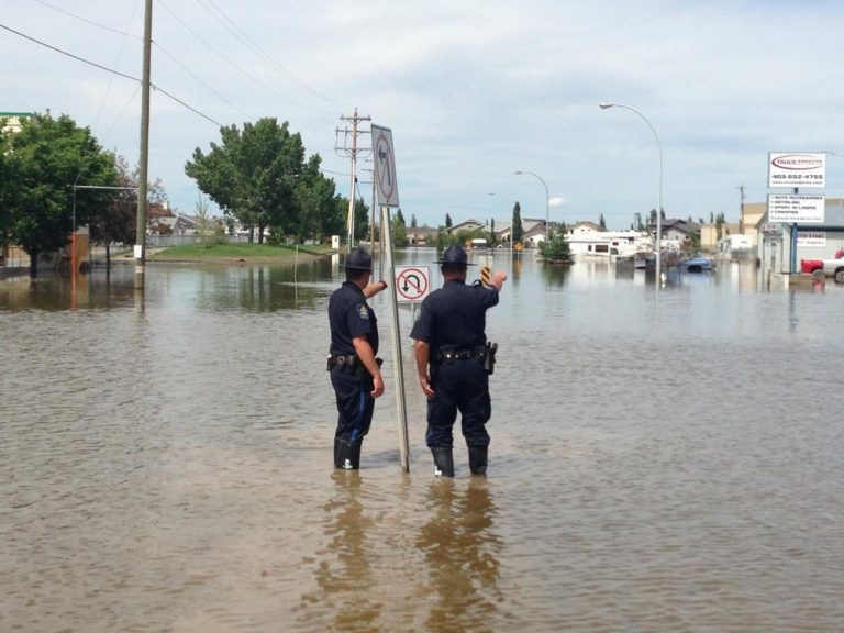 Photograph of two police officers standing in a flooded street.