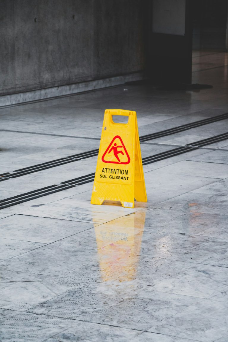 A photograph of a warning sign on a shiny stone floor.