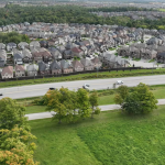 An aerial view of a housing sub-division bordering fields and forest