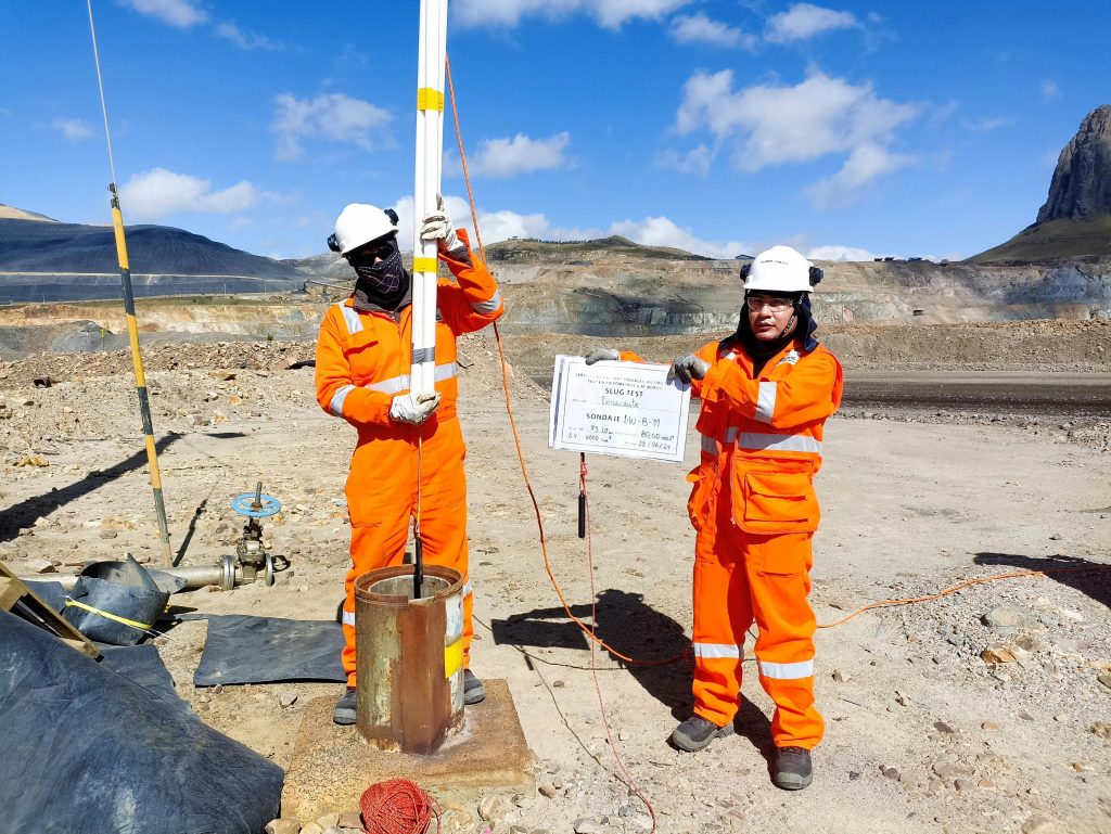 Two men in orange testing groundwater in Peru.