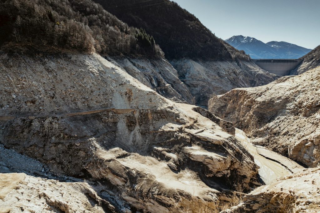 Photograph of a dry reservoir with a dam wall in the distance